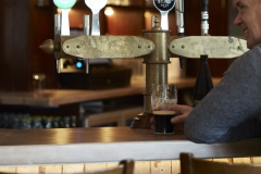 Bar details drinks seating, male customer enjoying pint of Guinness at bar counter